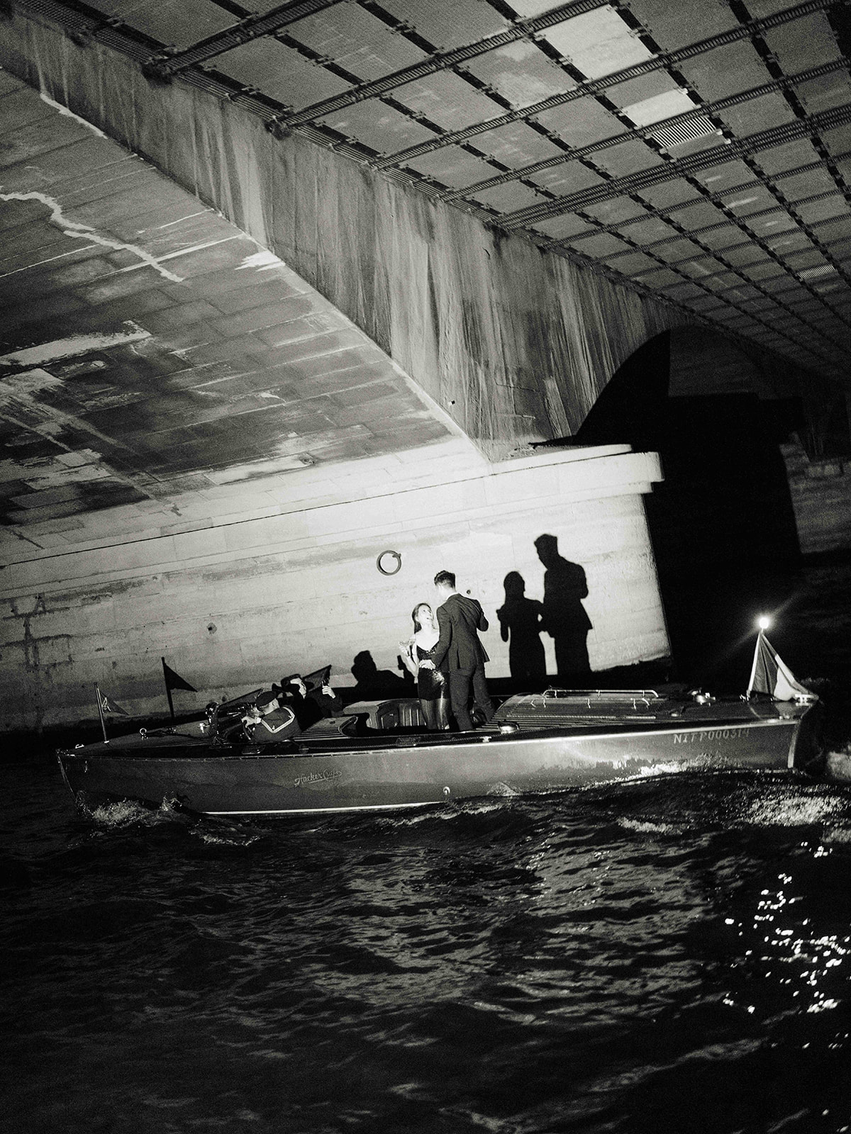 Cinematic black and white Paris proposal photo on a private boat beneath a Seine bridge